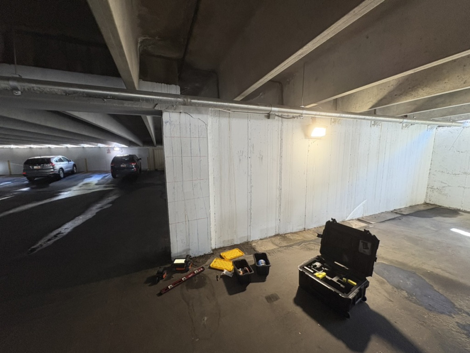 Parking garage bay with a cleaned white wall ready for scanning and cases of equipment staged on the floor