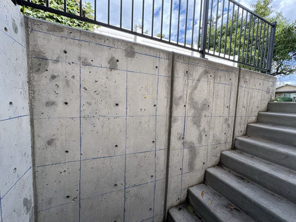 Stepped concrete retaining wall beside exterior stairs, marked with a blue crayon grid and the label B