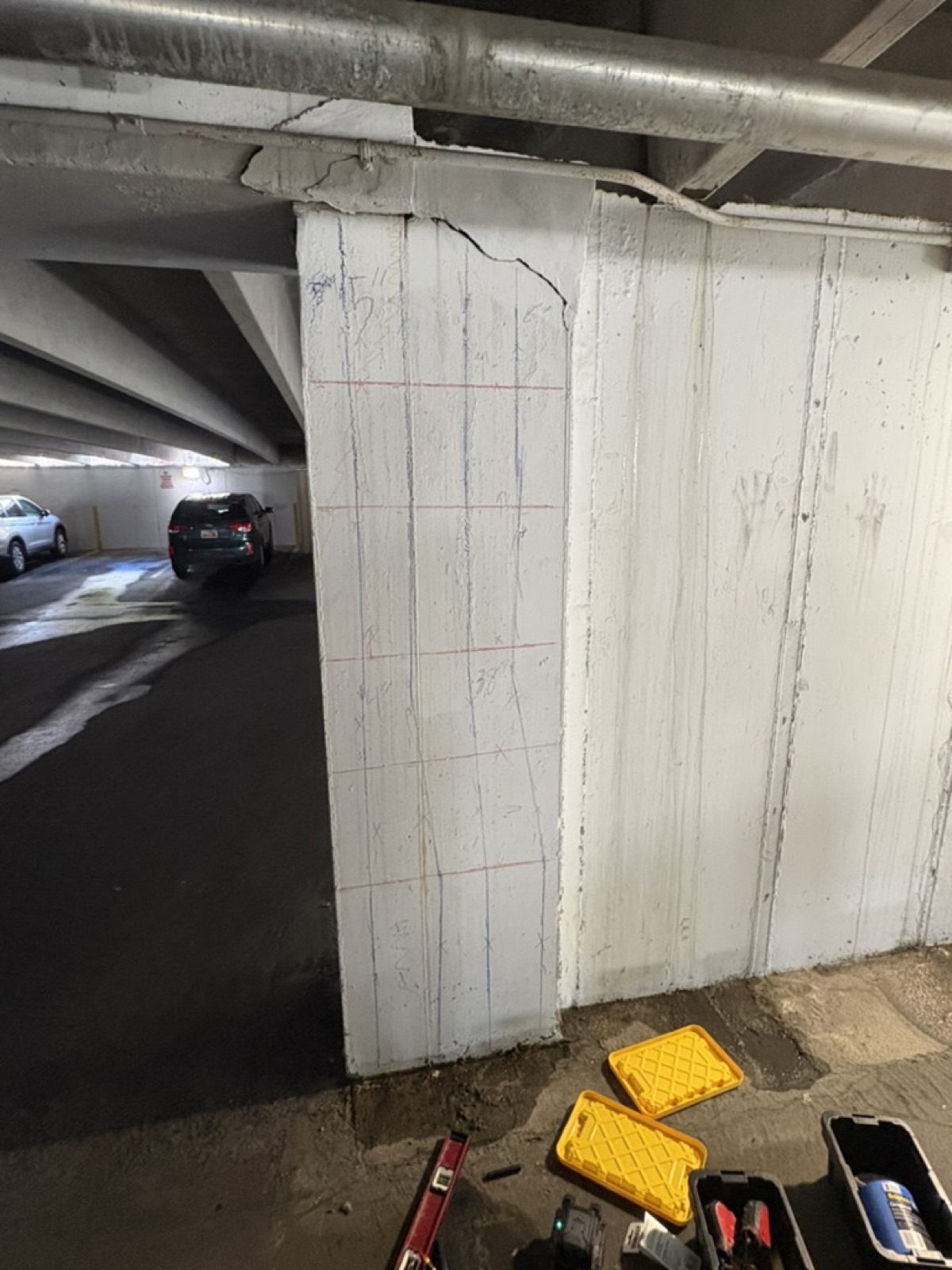 Marked wall panel in a parking garage with a diagonal crack running from its top corner